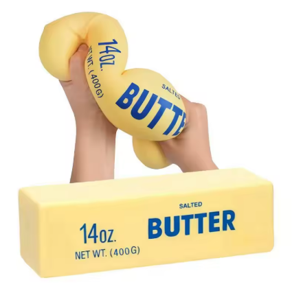 A yellow novelty butter sculpture shaped like two rounded bars held by two human hands, with a matching rectangular butter block below on a plain white background.