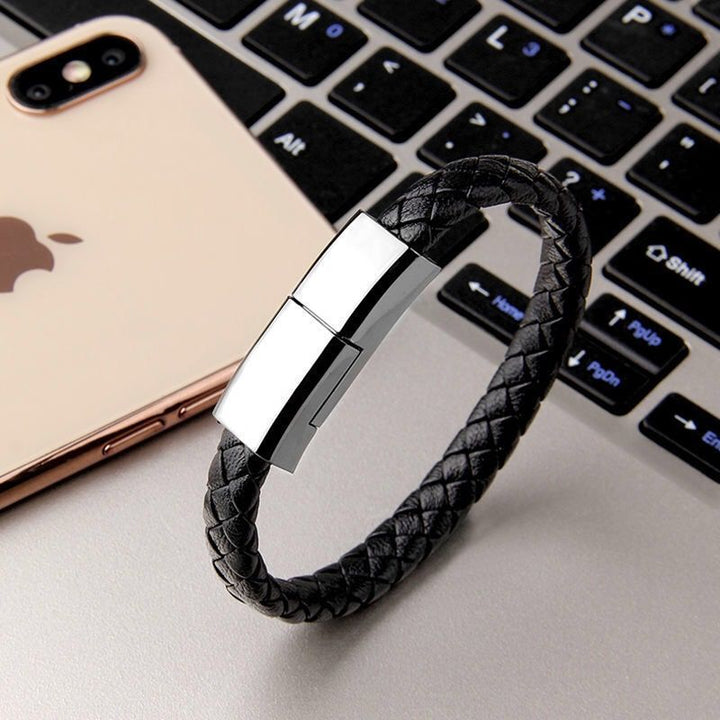 Black braided leather bracelet with metallic clasp on a laptop keyboard