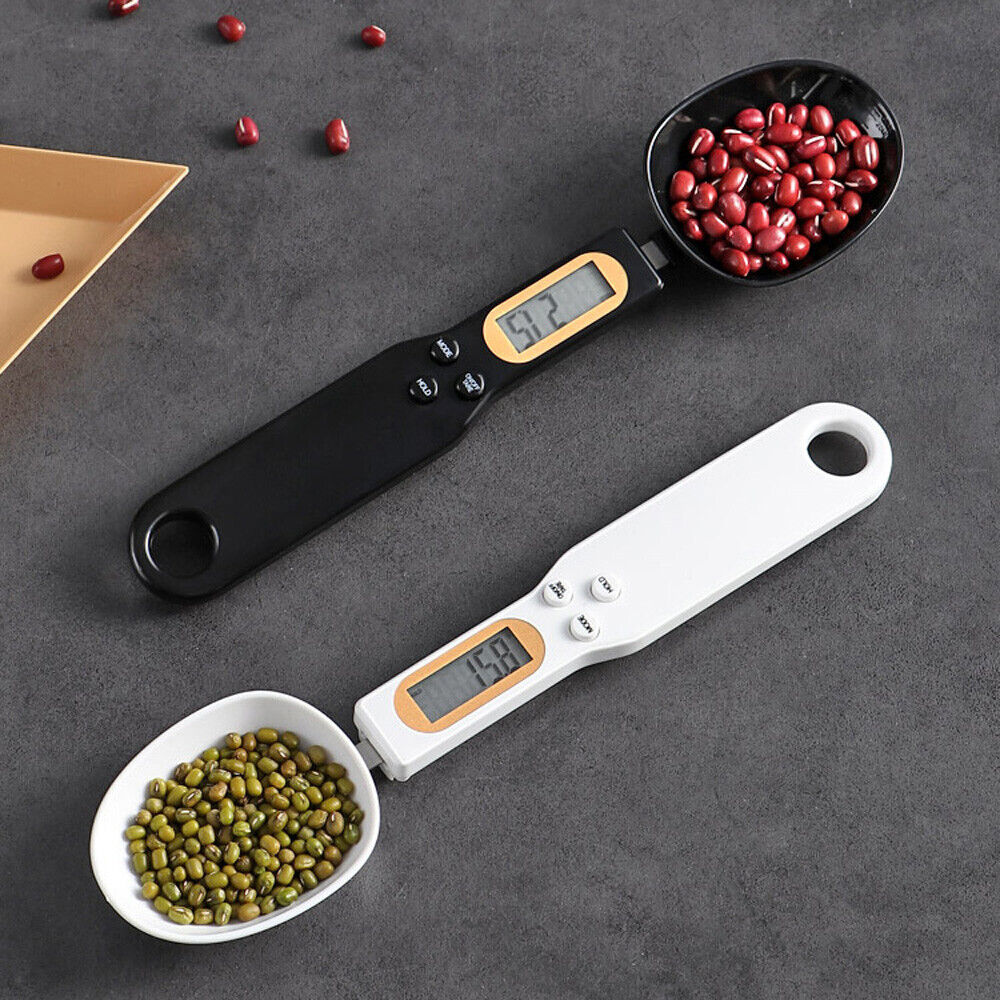 Digital measuring spoons with digital displays holding beans and peas on a gray surface.
