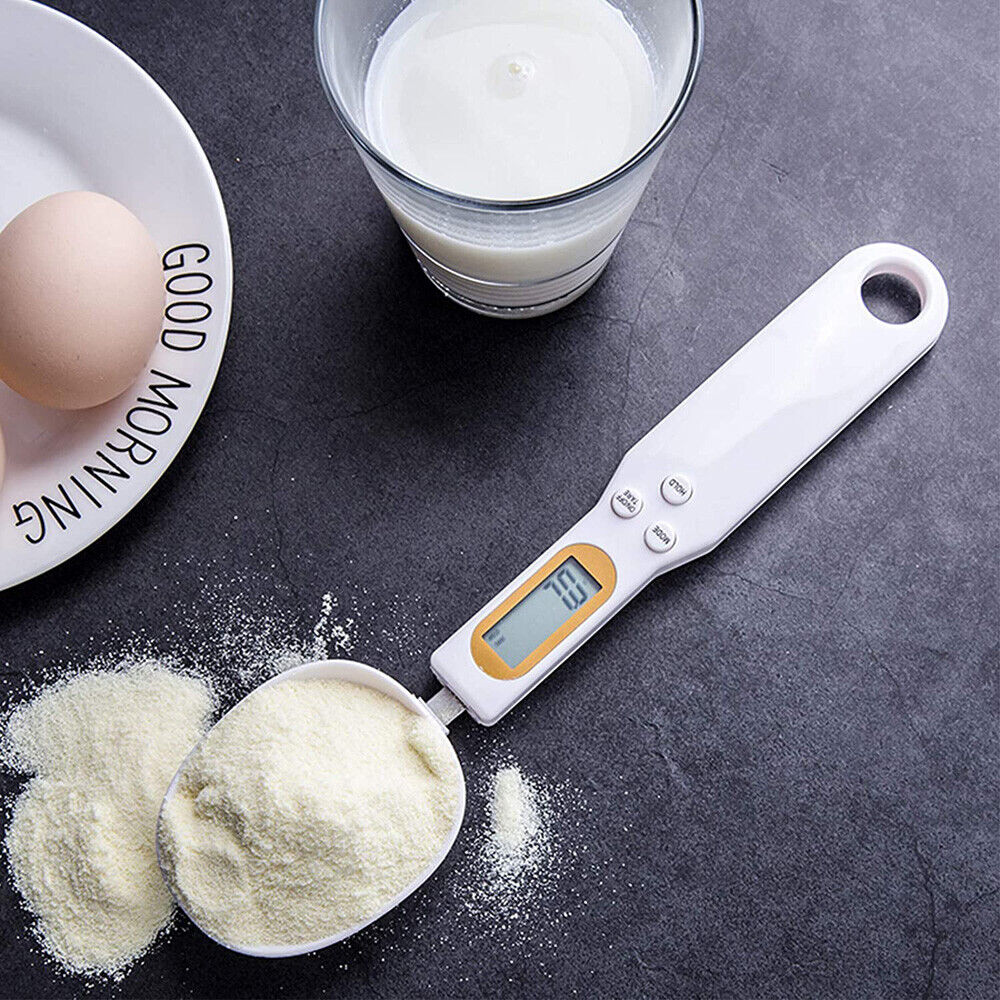 Digital measuring spoon with a glass of milk, egg, and powder on a dark surface