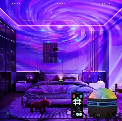 A bedroom scene illuminated by a purple and blue galaxy light projector, casting swirling starry patterns across the ceiling and walls. In the foreground, a small black dome-shaped projector with a rainbow-colored translucent top and a black remote control are shown.