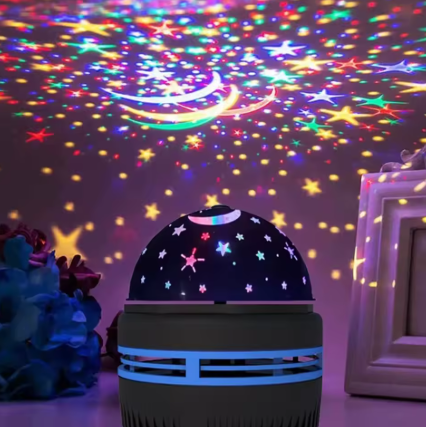 A dome-shaped night light projector with a star and moon design, casting colorful star and moon projections across a wall in a bedroom setting.