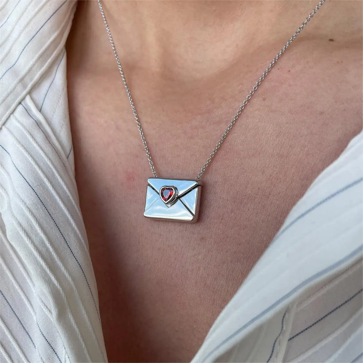Necklace with a heart-shaped pendant on a person wearing a white shirt.