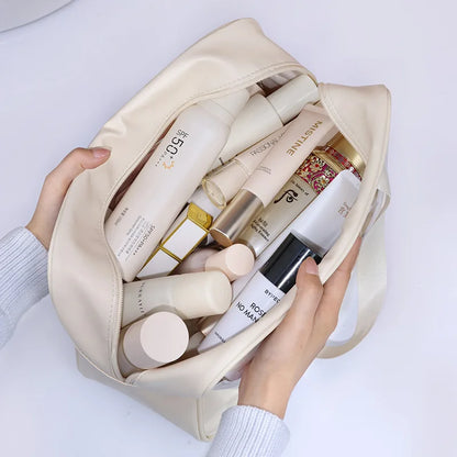 Beige cosmetic bag filled with skincare products held by a person against a white background
