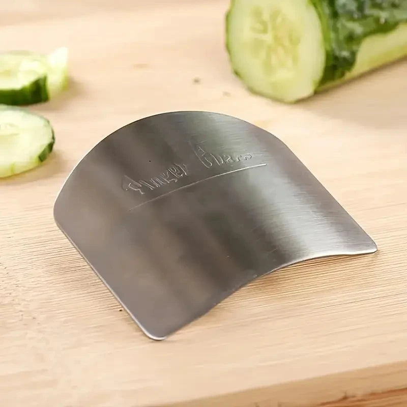 the steel finger guard on a wooden surface with a cucumber in the back ground