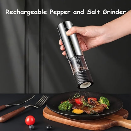 Hand holding a rechargeable pepper and salt grinder over a plate of food with utensils on a dark surface.