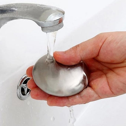 Metallic soap dish with water flowing from a faucet onto a white background