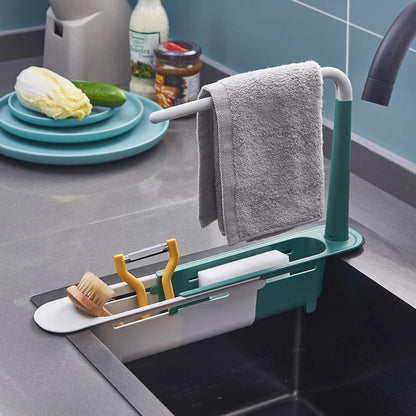 Kitchen sink caddy with cleaning tools and a towel on a kitchen counter.