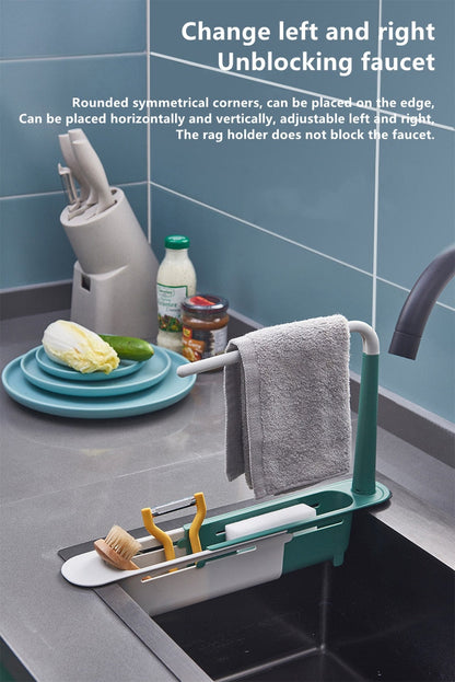 Kitchen sink with a green rack holding a towel, soap, and other items against a tiled wall.