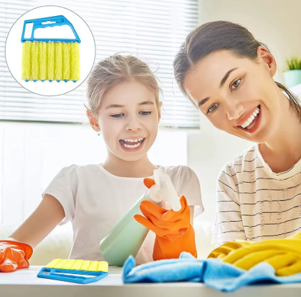 A woman and a young girl are smiling while cleaning at a table, with cleaning supplies including a yellow sponge brush, blue cloth, and orange gloves. An inset circle in the top-left shows the yellow sponge brush with a blue handle.