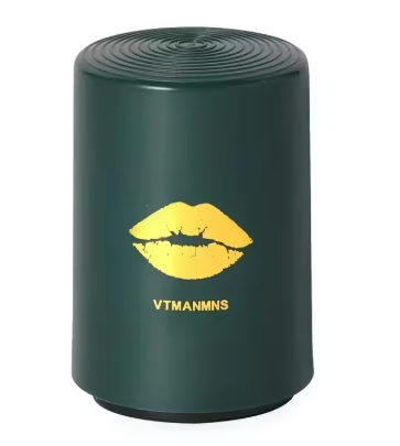 A dark green cylindrical speaker with a yellow lips graphic and the text 'VTMANMNS' printed on the front, set against a plain white background.